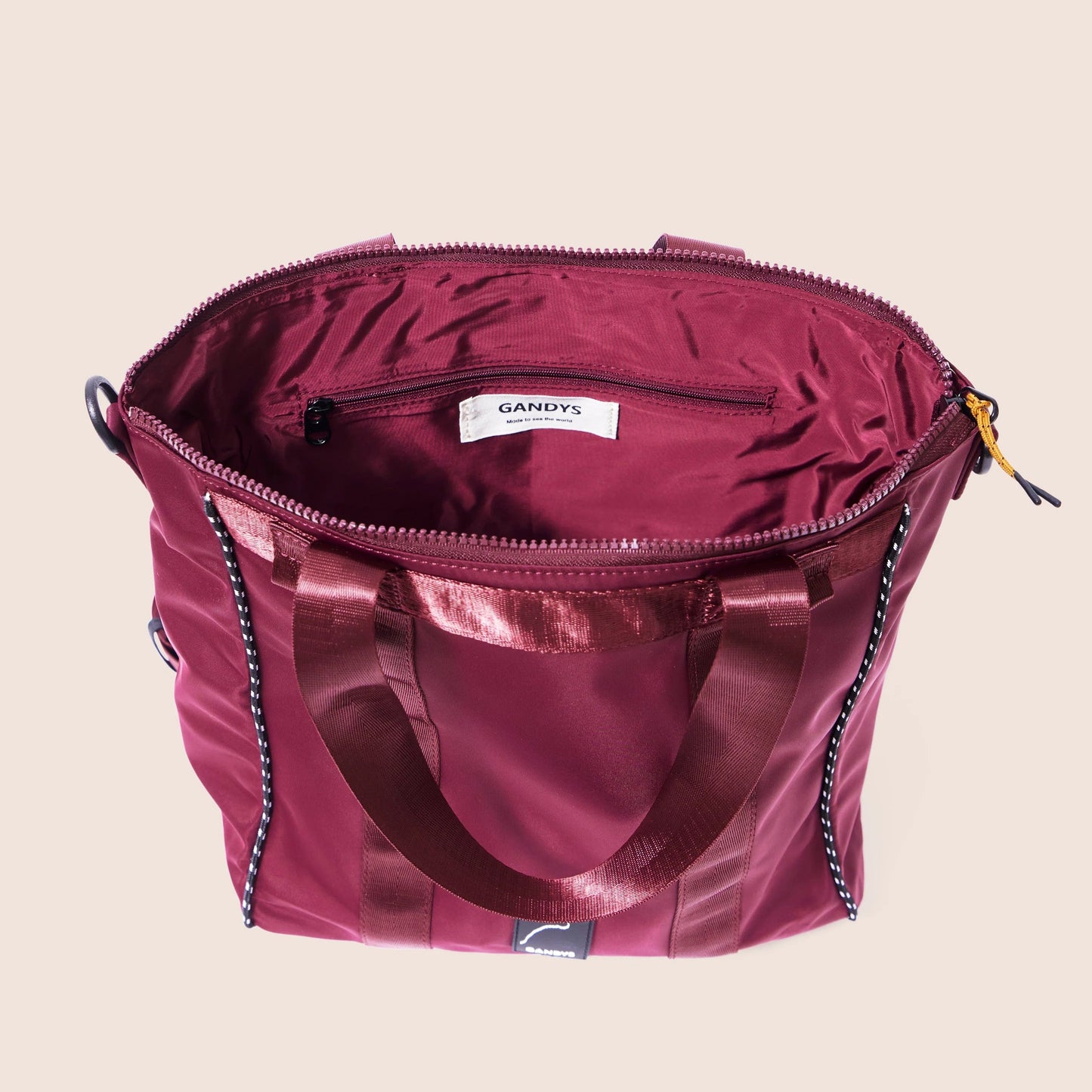 Maroon handbag with a visible brand label on a beige background