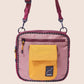 Pink crossbody bag with a yellow pocket on a beige background