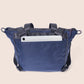 Blue crossbody bag with a white tablet inside on a beige background