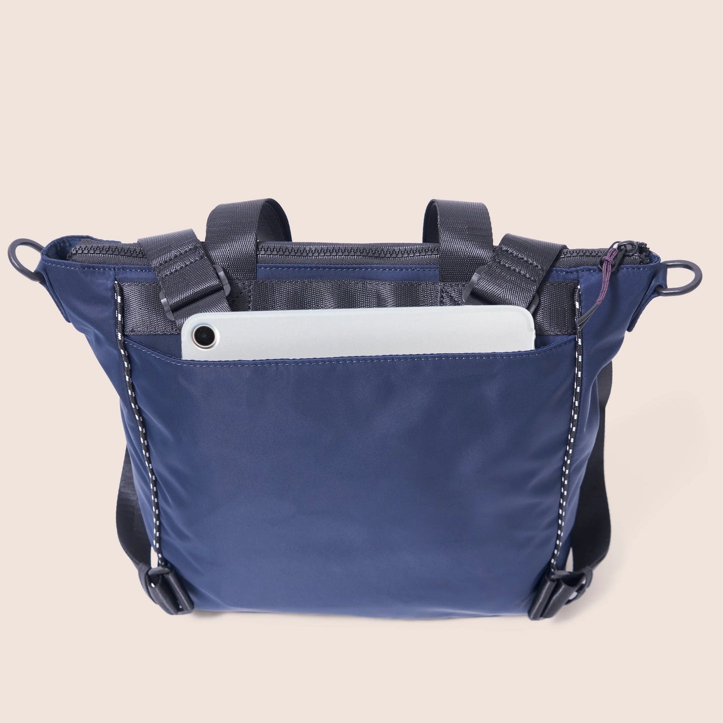 Blue crossbody bag with a white tablet inside on a beige background