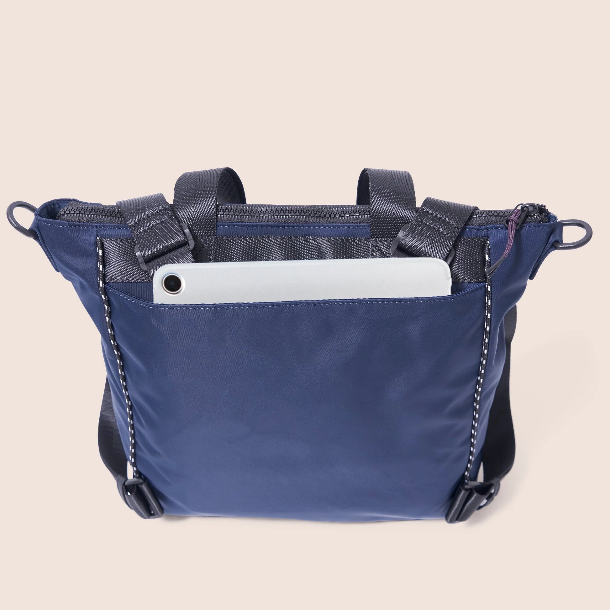 Blue crossbody bag with a white tablet inside on a beige background