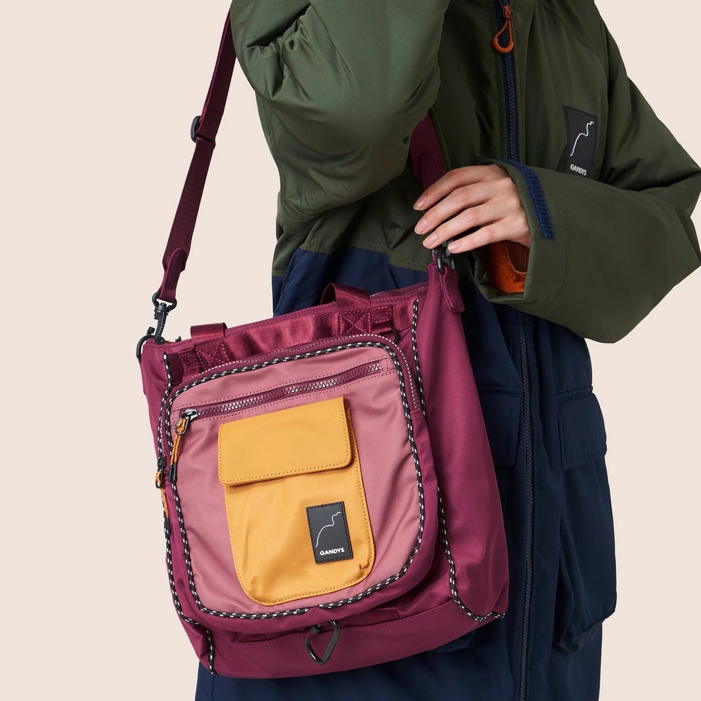 Person holding a purple bag with a yellow pocket against a beige background