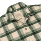A close-up of a green and cream plaid fleece button-up shirt by Hindbag, showing the collar, inner neck label, and front buttons.