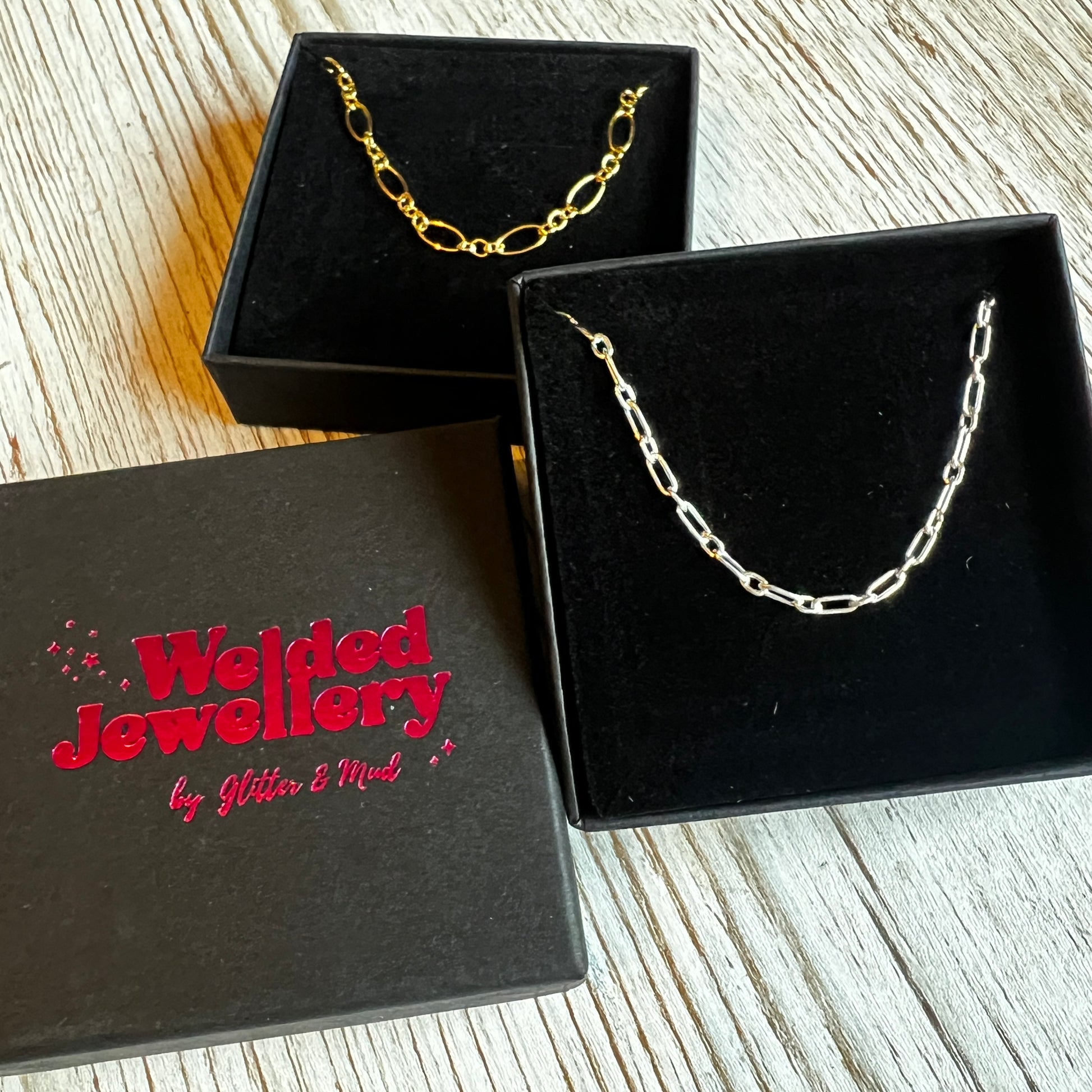 welded jewellery gift boxes with chains displayed on them on a wooden background 