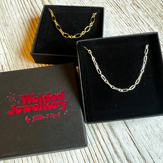 welded jewellery gift boxes with chains displayed on them on a wooden background 