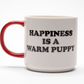 White mug with red handle and black 'Happiness is a warm puppy' text on a white background