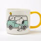 white mug with yellow handle. printed image of snoopy and woodstock with a blue camper van 