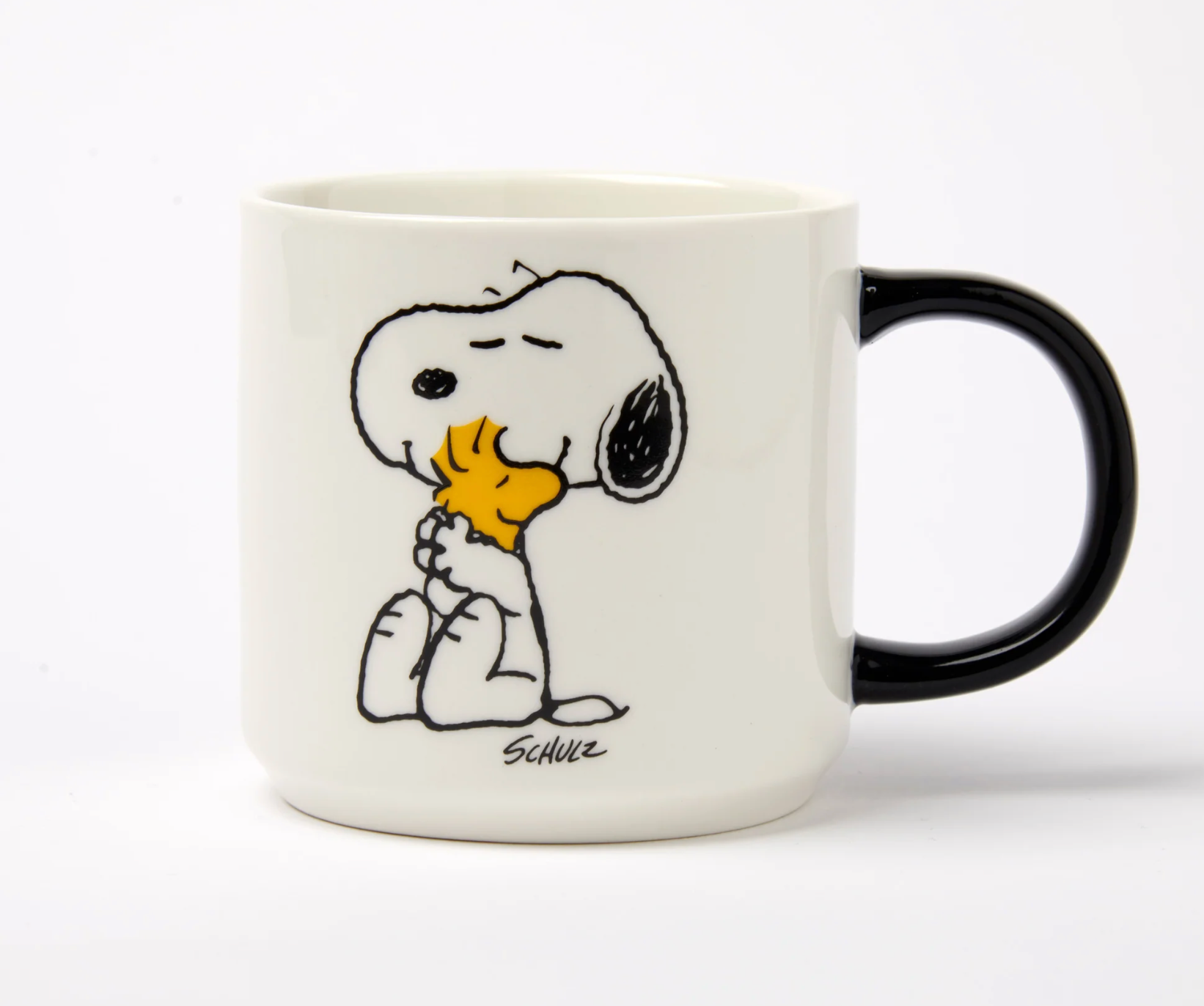 white mug with black handle. A cartoon snoopy and woodstock hugging 