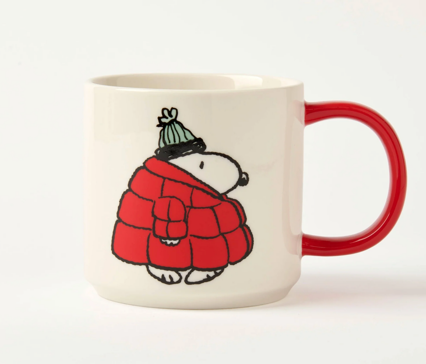 white mug with red handle. cartoon snoopy dog wearing a big red puffer coat and green bobble hat on a white background