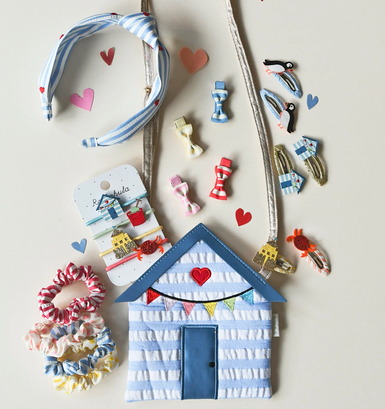 Wells Nest-the sea style Beach hut bag for Kids. white striped with colourful bunting and a red heart. surrounded by similar themed kids hair accesories on a white background 